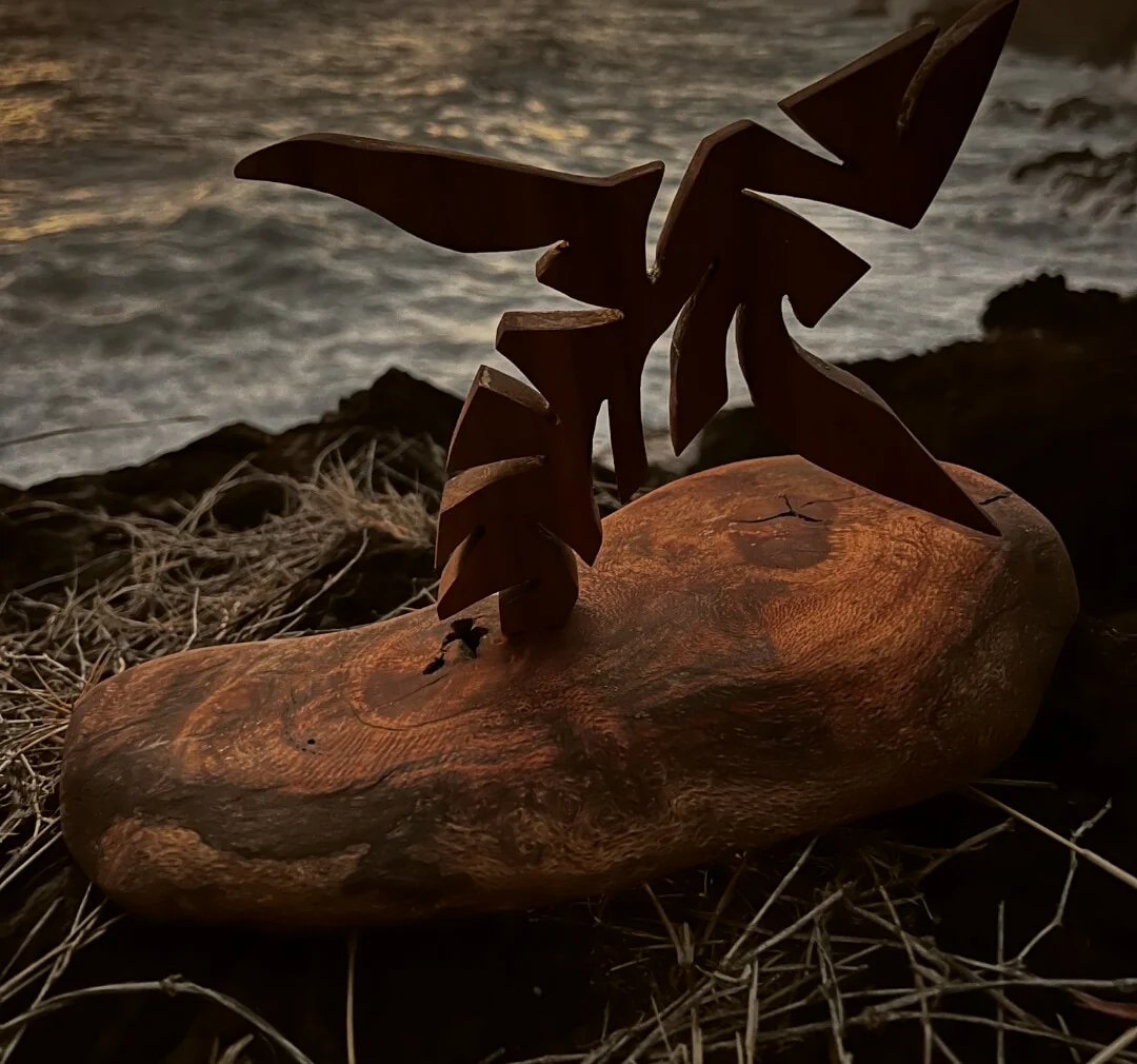 Baleine sculptée sur socle en bois flotté, face à l'océan au coucher du soleil